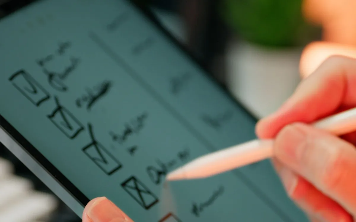 Mão com caneta desenhando o fluxo de telas de um aplicativo em um tablet