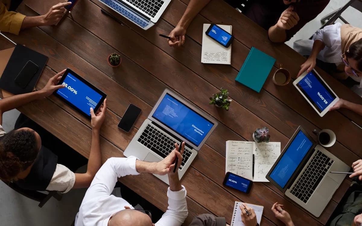 Equipe reunida em volta de uma mesa com notebooks e tablets