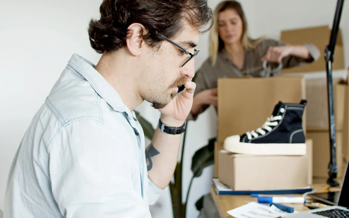 Empreendedor ao telefone com caixas de produtos ao fundo