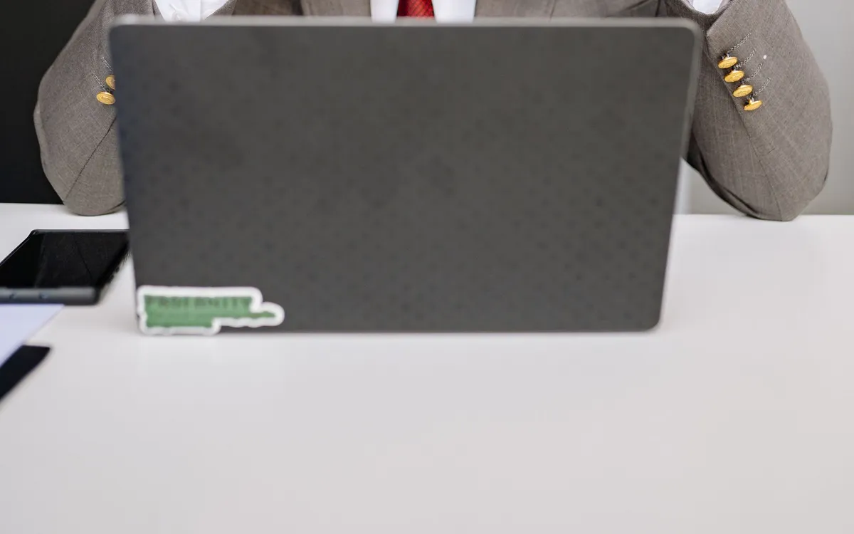 Profissional diante de um notebook, com o rosto escondido atrás da tela