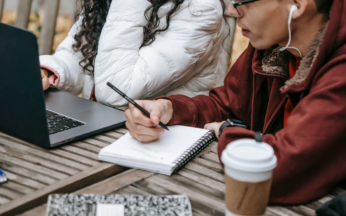 Duas pessoas planejando melhorias com notebook e caderno